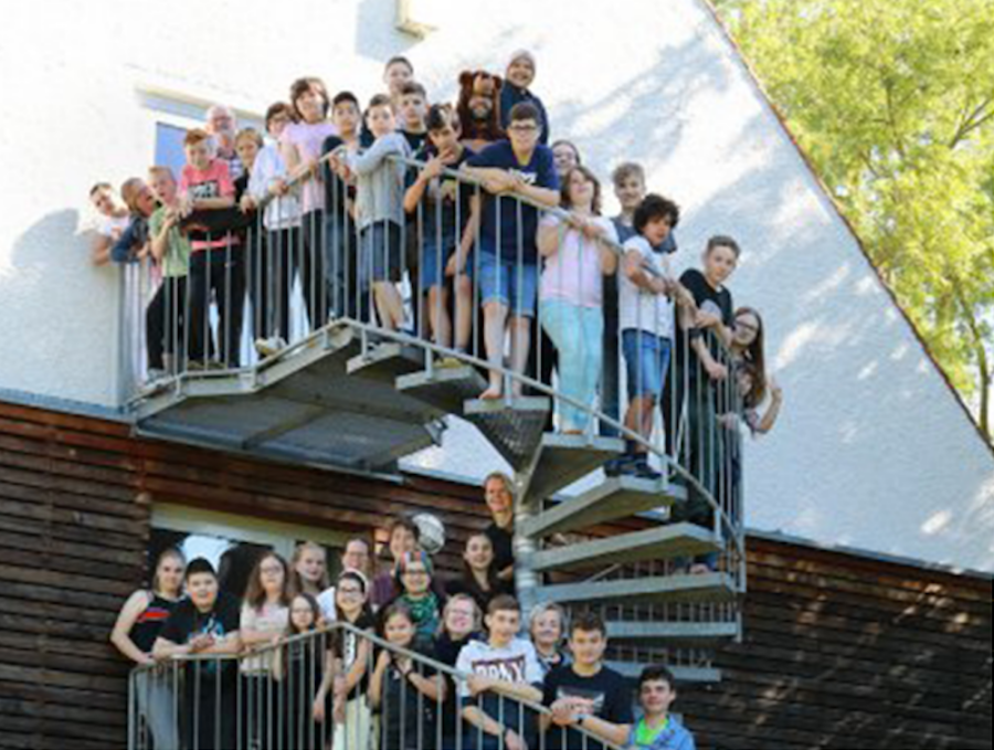 Kinder stehen auf Wendeltreppe vor weißem Haus