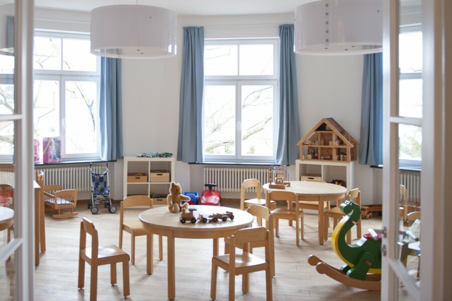 Spielzimmer im Blauen Haus mit kleinen Holztischen, Kinderstühlen und Spielgeräten