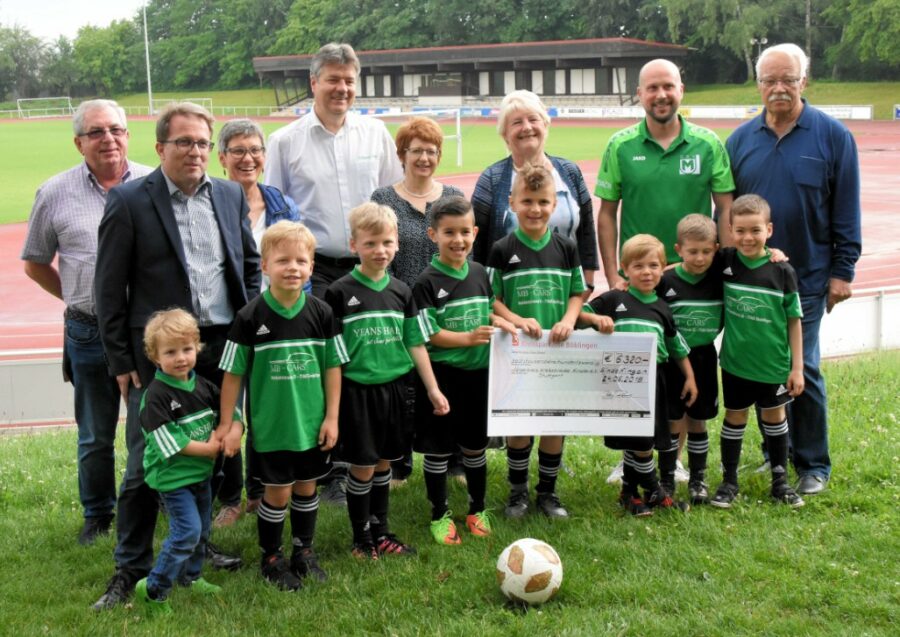 Junge Fußballspieler in grünen Trikots übergeben einen Spendencheck