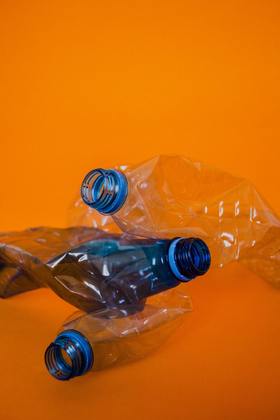 Leere und zerknüllte PET-Flaschen vor orangenem Hintergrund