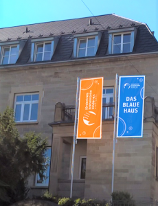Orangenes und blaues Banner vor dem Blauen Haus