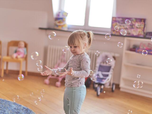 Junges Mädchen spielt in Spielzimmer mit Seifenblasen