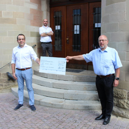 Zwei Vertreter der Zahnärzte am Rosenberg übergeben dem Vorstandsmitglied Michael Wünsch einen Spendencheck vor dem Blauen Haus