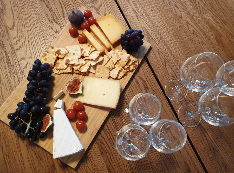 Holztisch mit Tablett mit Käse, Trauben und leeren Weingläsern
